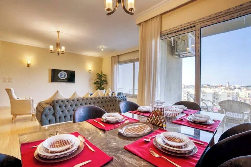 A dining area with a large table set for four, a sofa, and a view of the city.