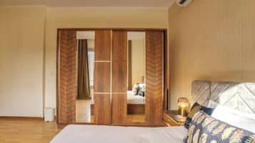 A bedroom with a bed, a nightstand with a lamp, and a wooden wardrobe with a mirror.