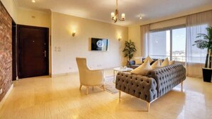 A modern living room with a sofa, armchair, and a TV mounted on the wall. - The Suite, Palm Hills - VG631, Residential Suites near AUC by ELEGANT (New Cairo City)