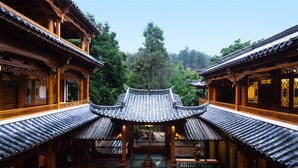 A traditional courtyard with wooden buildings, a central water feature, and a tiled roof. - GRAND JOLI (Lijiang)