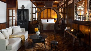A traditional room with a bed, a sofa, a table, and a decorative vase. - GRAND JOLI (Lijiang)