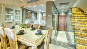 Un coin repas avec une table à plateau en verre, des chaises rembourrées et une cuisine en arrière-plan.
