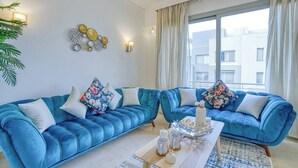 A modern living room with two blue sofas, a coffee table, and decorative wall art.