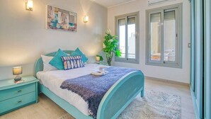 A bedroom with a bed, bedside tables, a wall-mounted light, a window, and a plant. - The Suite, Palm Hills - VG924, Residential Suites near AUC by ELEGANT (New Cairo City)