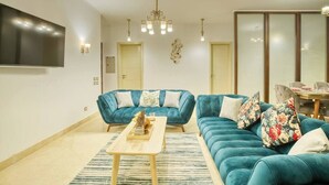 A modern living room with a blue sofa set, a wooden coffee table, and a chandelier.