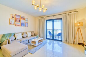 A modern living room with a sofa, ottoman, coffee table, and artwork on the wall. - The Lofts across AUC - A512, LOFTS BY ELEGANT - WITH POOL (New Cairo City)