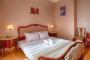 A hotel room with a large bed, two bedside tables, a chair, and artwork on the walls. - The Suite, Palm Hills - V1811, Residential Suites near AUC by ELEGANT (New Cairo City)