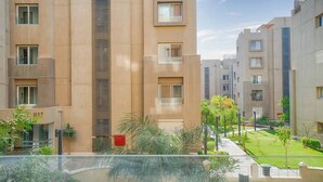 A modern residential building with multiple floors, balconies, and a well-maintained garden area. - The Suite, Palm Hills - V1811, Residential Suites near AUC by ELEGANT (New Cairo City)