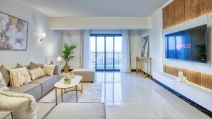 A modern living room with a sofa, coffee table, and a TV mounted on the wall. - The Lofts across AUC - D108, LOFTS BY ELEGANT - WITH POOL (New Cairo City)