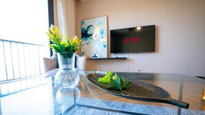 A modern living room with a glass table, a vase with green plants, a flat-screen TV displaying "NETFLIX", and a painting on the wall. - The Lofts across AUC - C703, LOFTS BY ELEGANT - WITH POOL (New Cairo City)