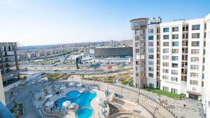 A modern hotel with a rooftop pool, multiple floors, and a view of the cityscape. - The Lofts across AUC - C703, LOFTS BY ELEGANT - WITH POOL (New Cairo City)