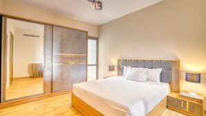 A bedroom with a large bed, a nightstand, a mirror, and a wardrobe. - The Lofts across AUC - C703, LOFTS BY ELEGANT - WITH POOL (New Cairo City)