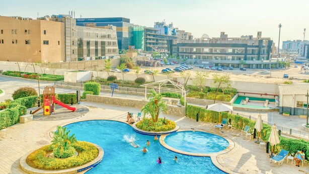 Un área de piscina con varias piscinas, un tobogán y una zona de juegos.