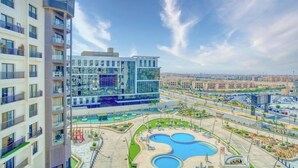 A modern hotel with multiple floors, a rooftop pool area, and a view of the surrounding cityscape. - The Lofts across AUC - A513, The Lofts by Elegant (New Cairo City)
