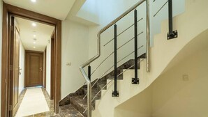 A staircase with metal railings and marble steps leading to an upper floor. - The Lofts across AUC - A513, The Lofts by Elegant (New Cairo City)