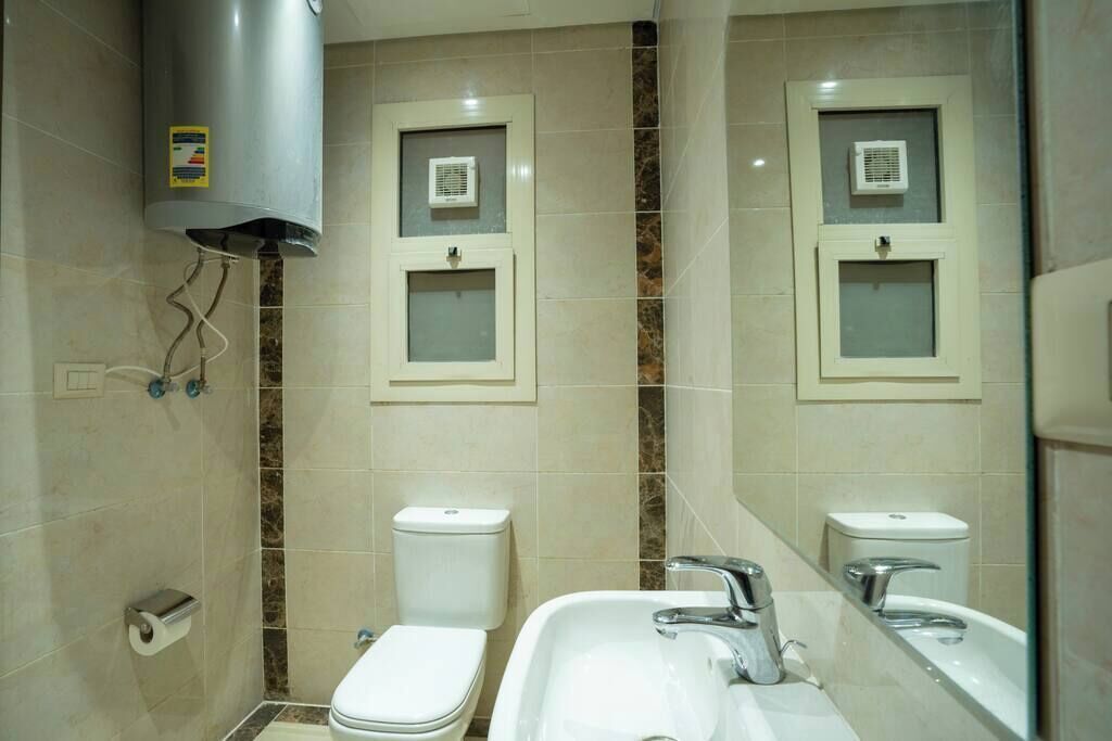 A bathroom with two toilets, a sink, and a mirror.