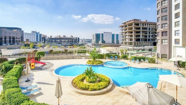 A rooftop swimming pool with lounge chairs and a children's play area. - The Lofts across AUC - A513, The Lofts by Elegant (New Cairo City)