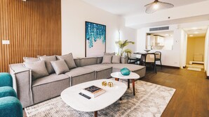 A modern living room with a sectional sofa, a coffee table, and a dining area with a small table and chairs. - The Lofts across AUC - A513, The Lofts by Elegant (New Cairo City)