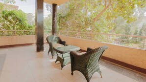 A covered outdoor seating area with wicker furniture and a view of trees.