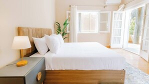 A bedroom with a bed, bedside table, lamp, and a window with curtains.