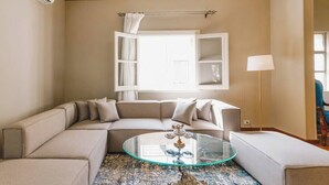 A living room with a beige sectional sofa, a glass coffee table, and a patterned rug.