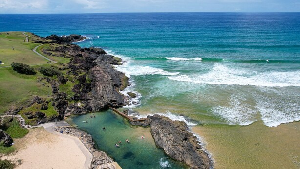 A coastal landscape with a rocky shoreline, clear waters, and a sandy beach. - Periwinkle - Ideal Beachfront Retreat Near Main Street with Ceiling Fans, Wi-Fi & Air Con (Sawtell)