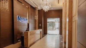 Zona de recepción de un hotel con mostrador, una araña y un cartel que dice "Nyoum of New Cairo".