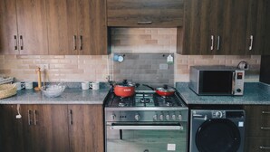 A kitchen with wooden cabinets, a stove, a microwave, and a washing machine.