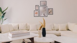 A modern living room with a white sofa, a coffee table, and a vase with dried plants.
