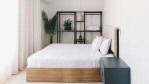 A modern bedroom with a wooden bed frame, a built-in shelving unit, and a bedside table. - The Seven Six Near Waterway 5A - 4, THE SEVEN SIX near WATERWAY 5A MALL By ELEGANT (New Cairo City)