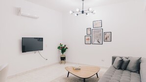 Un salon moderne avec un canapé gris, une table basse en bois et un téléviseur à écran plat fixé au mur.
