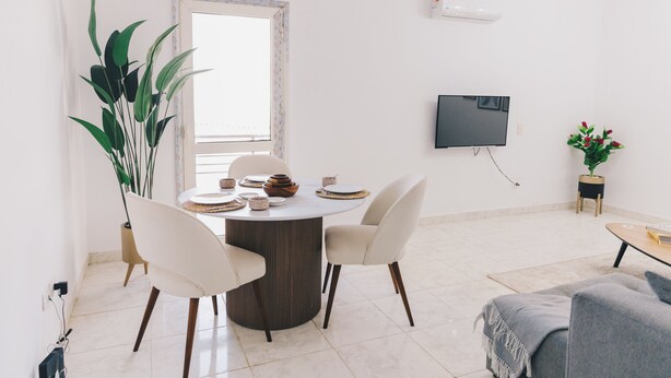 Un espace repas moderne avec une table ronde, des chaises et un téléviseur fixé au mur.