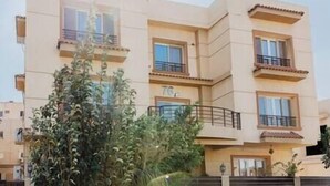 A multi-story residential building with balconies and a number '70' visible on the facade. - The Seven Six Near Waterway 5A - 10, THE SEVEN SIX near WATERWAY 5A MALL By ELEGANT (New Cairo City)