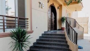 A staircase leading to a building entrance with a number '76' above the door. - The Seven Six Near Waterway 5A - 10, THE SEVEN SIX near WATERWAY 5A MALL By ELEGANT (New Cairo City)