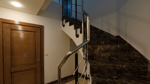 A staircase with a metal handrail, a wooden door, and a stone wall.