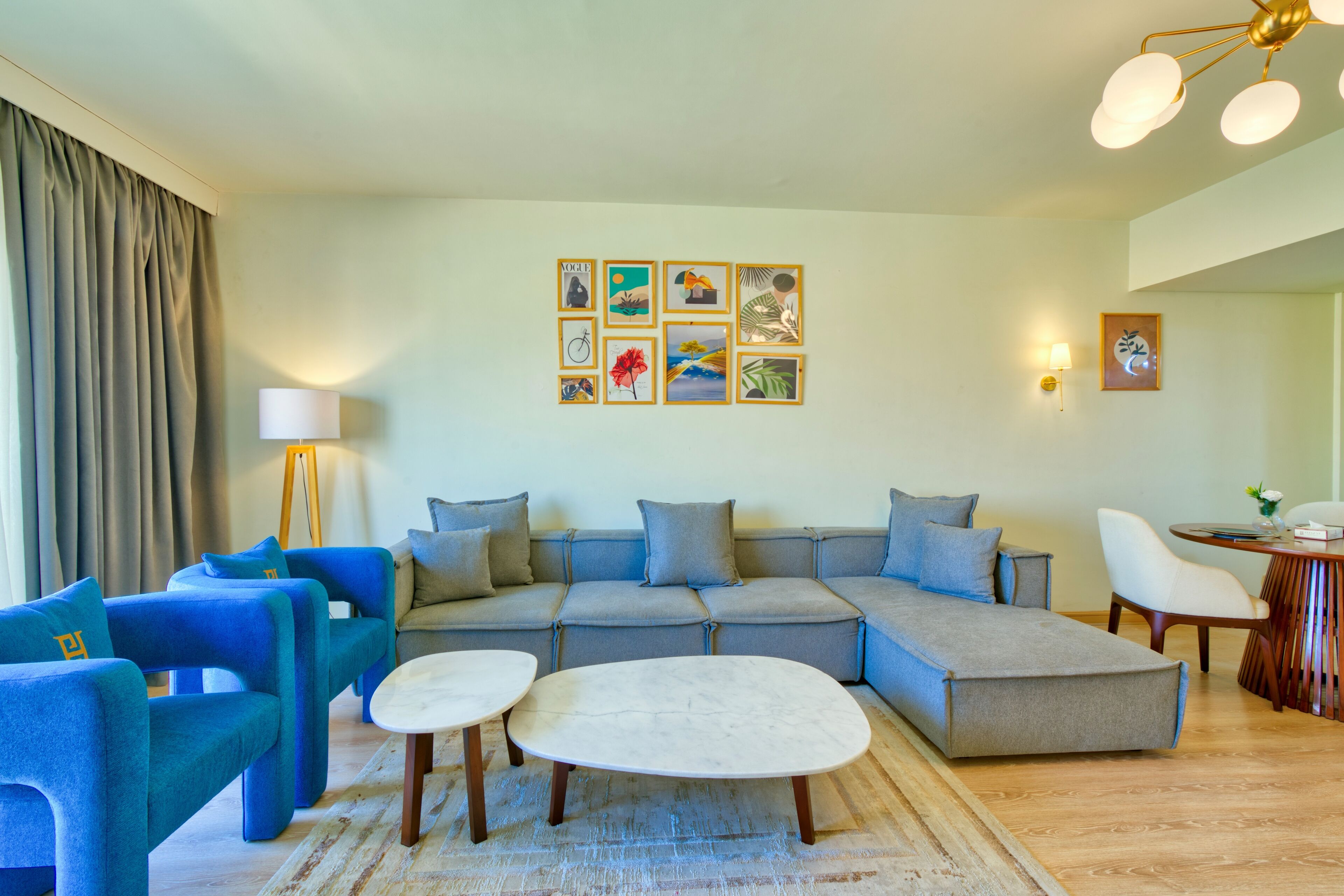 Ein modernes Wohnzimmer mit einer Eckcouch, blauen Sessel und einem runden Couchtisch.