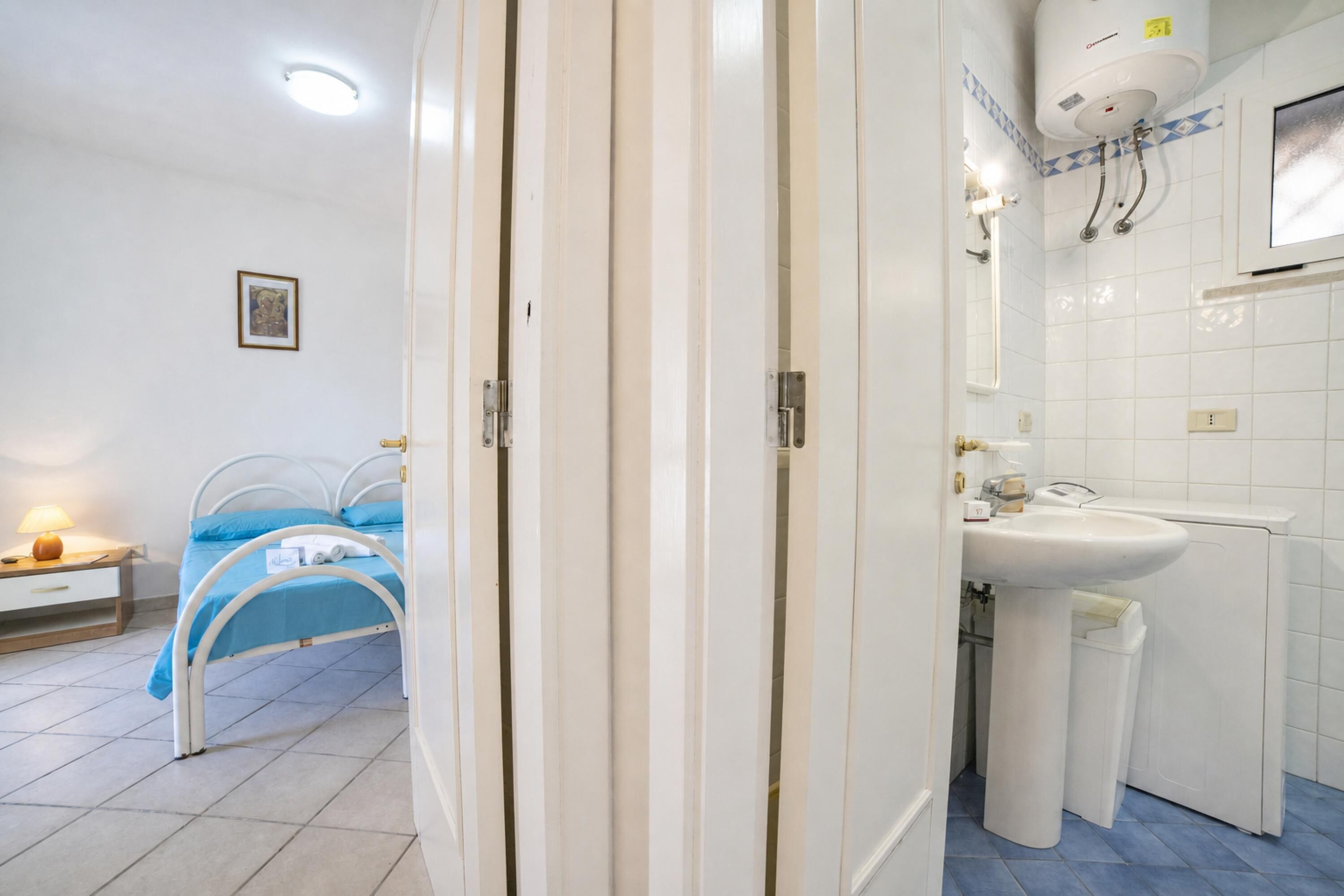Een slaapkamer met een bed, nachtkastje en een klein tafeltje.