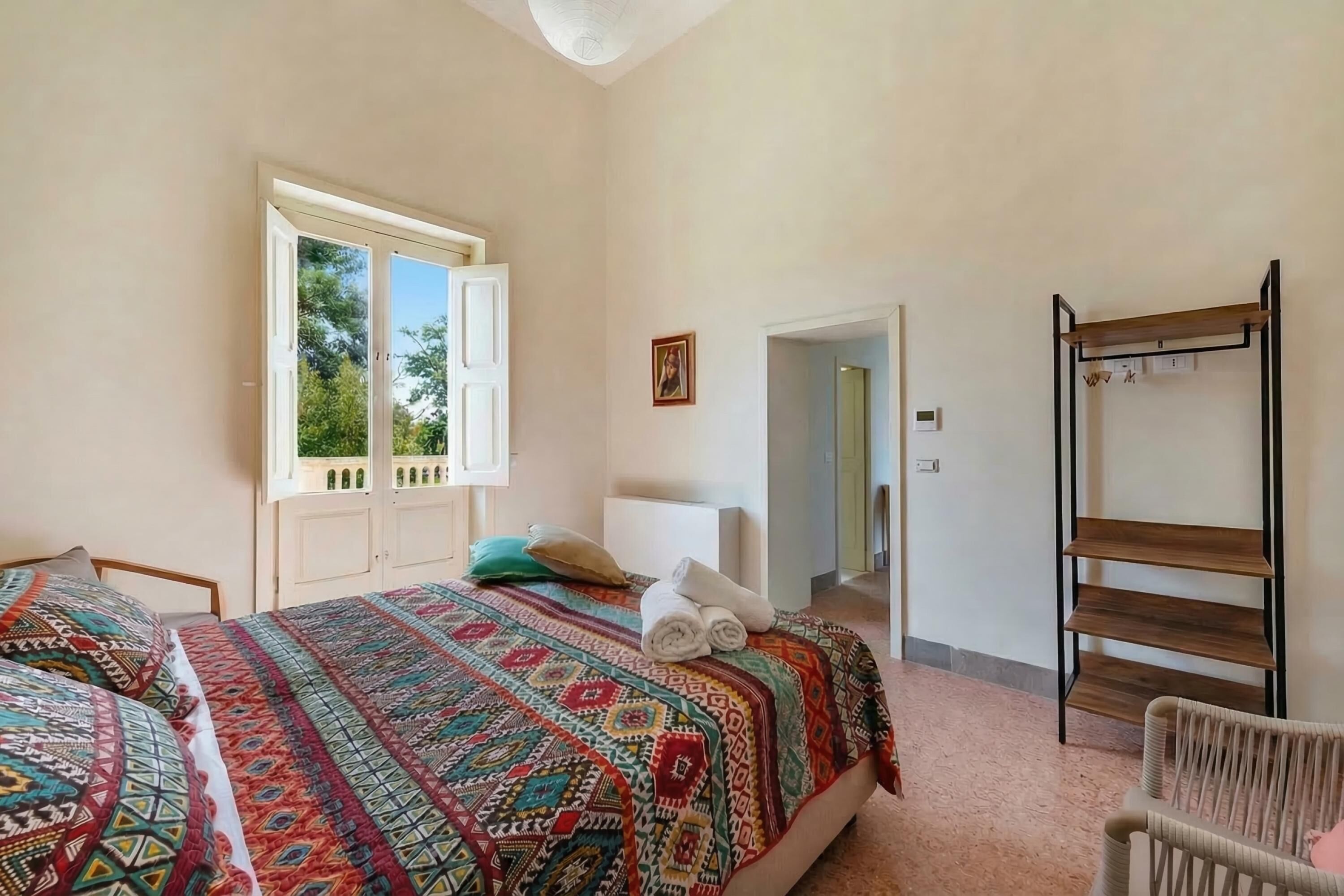 Ein Schlafzimmer mit Bett, Fenster, Tür und einem Holzboden.