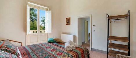 Ein Schlafzimmer mit Bett, Fenster, Tür und einem Holzboden.