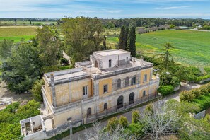 A historic building with a courtyard, surrounded by lush greenery and fields. - Vallone Apartments (Galatina)