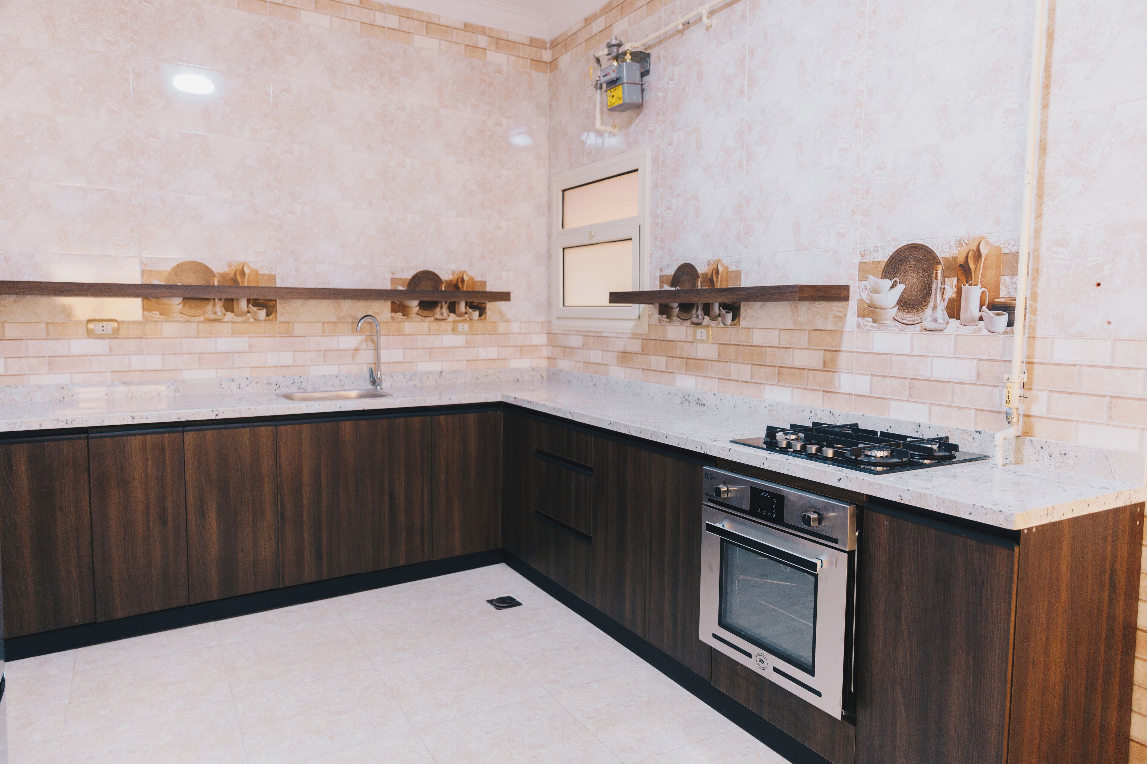 A modern kitchen with dark wood cabinets, a stainless steel oven, and a gas stove.