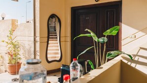 A hotel entrance with a dark wooden door, a reception desk with water bottles, a potted plant, and a sign above the door. - VIDA in Yasmeen - V201, VIDA Garden View Apartment (New Cairo City)