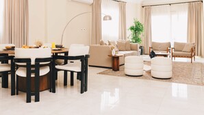 A modern living room with a dining area, a sofa set, ottomans, a plant, and a large window with curtains. - VIDA in Yasmeen - V201, VIDA Garden View Apartment (New Cairo City)