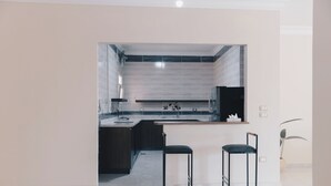 Una cocina moderna con una isla central, dos taburetes de bar y un horno empotrado.