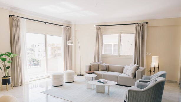 Un salón amplio con sofá, sillones, una mesita de centro y una planta en maceta.