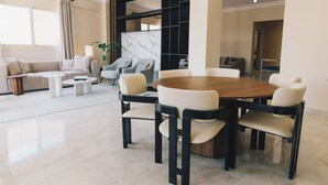 Una sala de estar moderna con una mesa redonda de madera para comer, rodeada de sillas, un sofá y una mesa de centro.