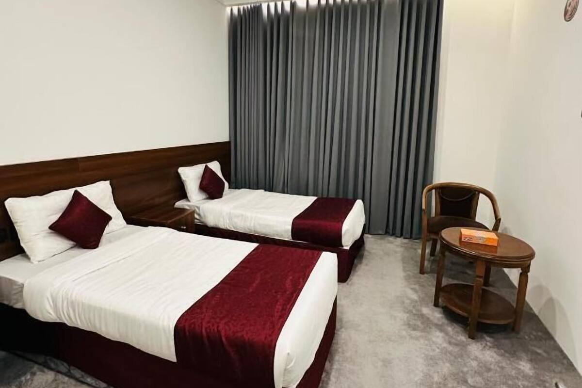 Habitación de hotel con dos camas, una mesita y una silla.