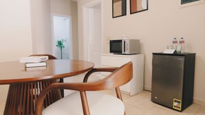 Une cuisine compacte comprenant une table à manger, des chaises, un four à micro-ondes, un réfrigérateur et un petit placard.