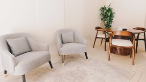 Une pièce moderne avec deux fauteuils gris, une table à manger en bois avec quatre chaises et une plante en pot.