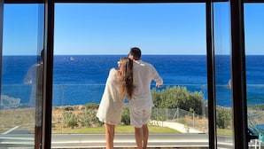 Una pareja está de pie en un patio de piedra con vistas al mar.